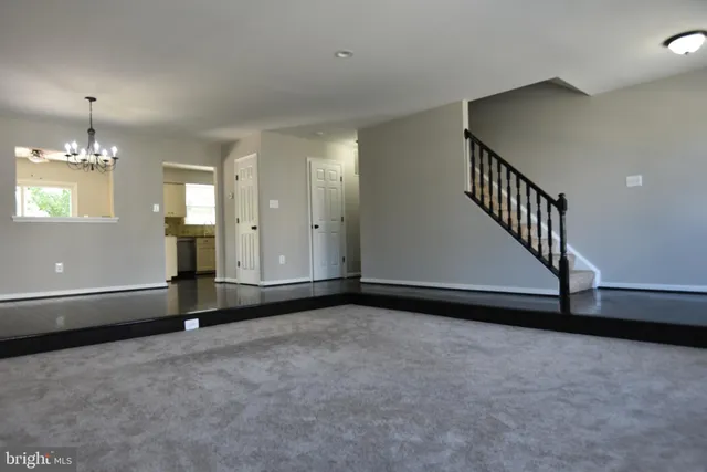 a view of an empty room with a chandelier fan
