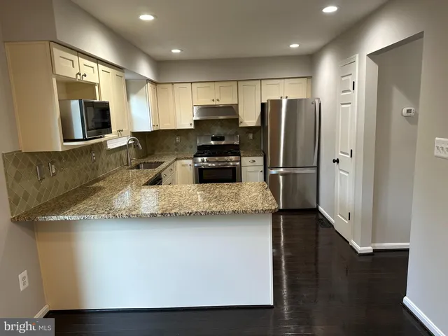 a kitchen with granite countertop a refrigerator and a sink
