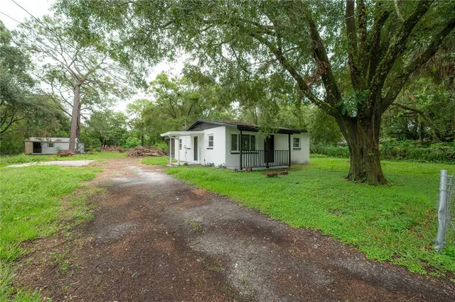 a view of backyard of house with wooden deck and large trees