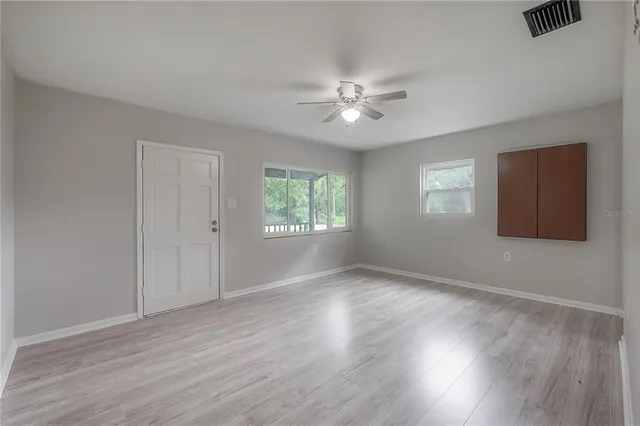 a view of an empty room with wooden floor and a window