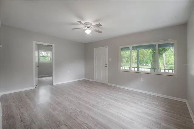 a view of an empty room with wooden floor and a window