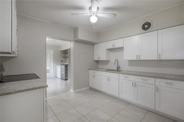 a large white kitchen with granite countertop white cabinets and a sink