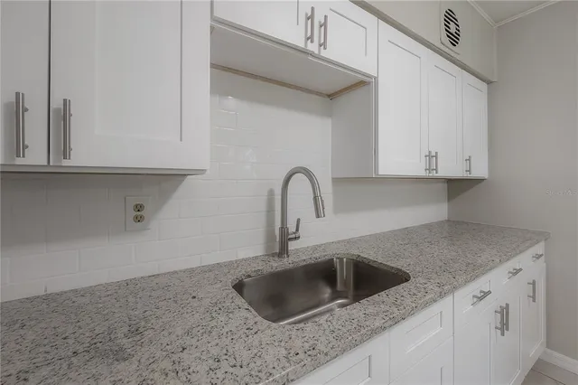 a kitchen with granite countertop a sink and white cabinets