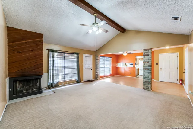 a view of an empty room with a fireplace and a window