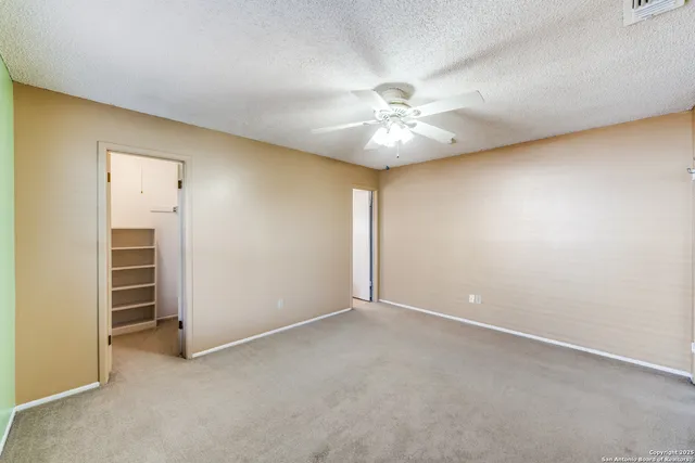 an empty room with closet and a ceiling fan