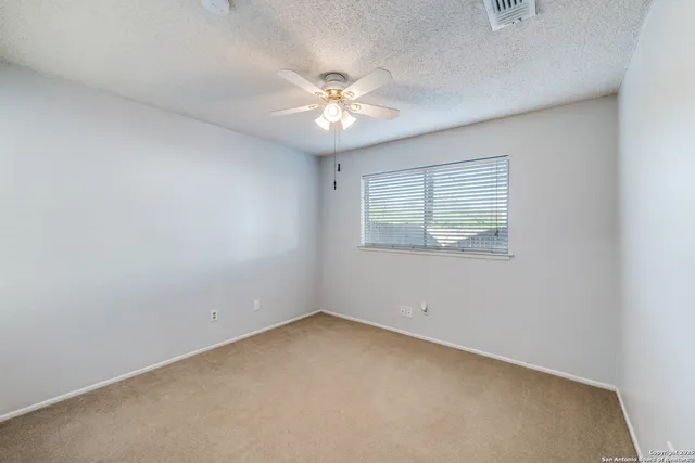 an empty room with a window and a fan