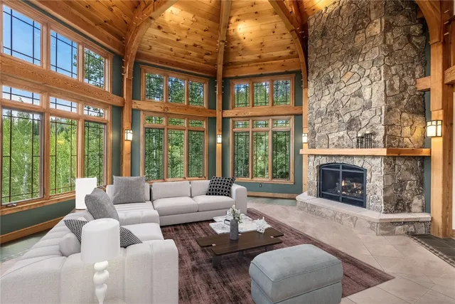 a living room with furniture a fireplace and floor to ceiling windows