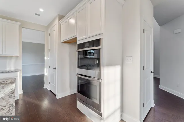 a kitchen with stainless steel appliances granite countertop a sink a stove a refrigerator and white cabinets
