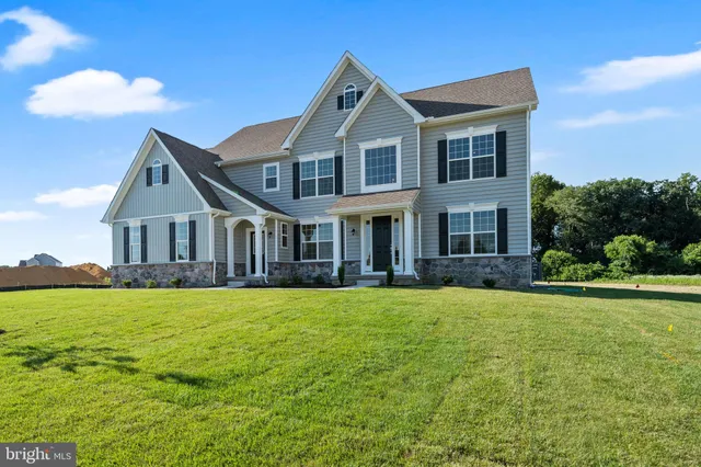 a front view of house with yard and trees in the background