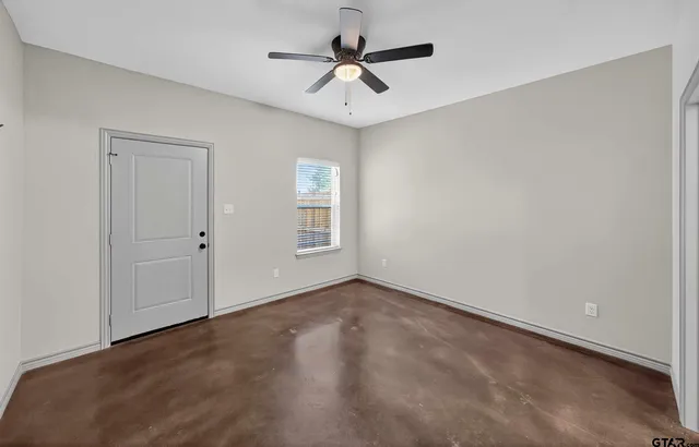 an empty room with windows and fan