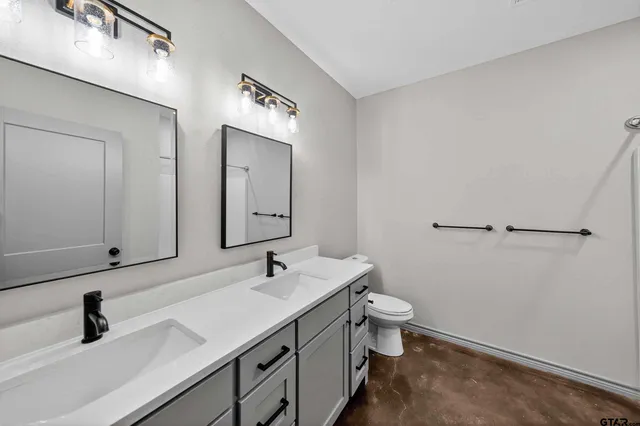 a bathroom with a double vanity sink toilet and mirror