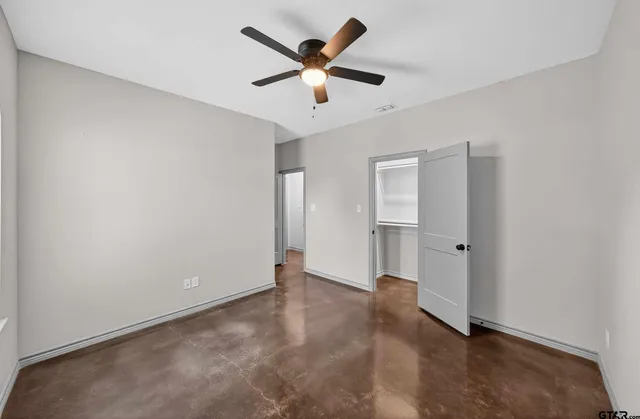 an empty room with closet and ceiling fan