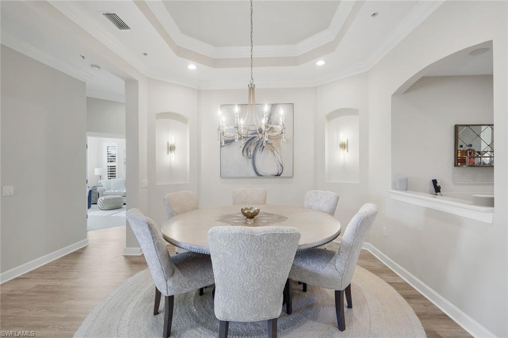 a dining room with furniture a chandelier and wooden floor