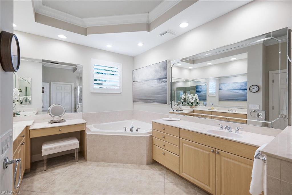 9201 Quartz Lane, Unit 202 Naples, FL 34120 - Photo 21 of 48 a bathroom with a double vanity sink a large mirror and a bathtub