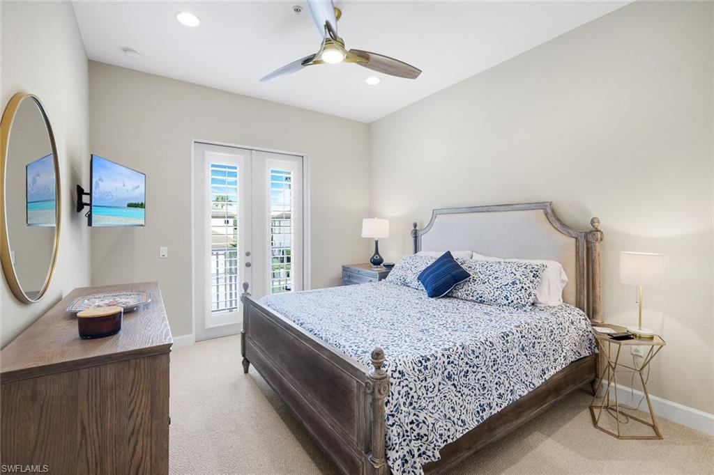 9201 Quartz Lane, Unit 202 Naples, FL 34120 - Photo 23 of 48 a bedroom with a large bed and a chandelier
