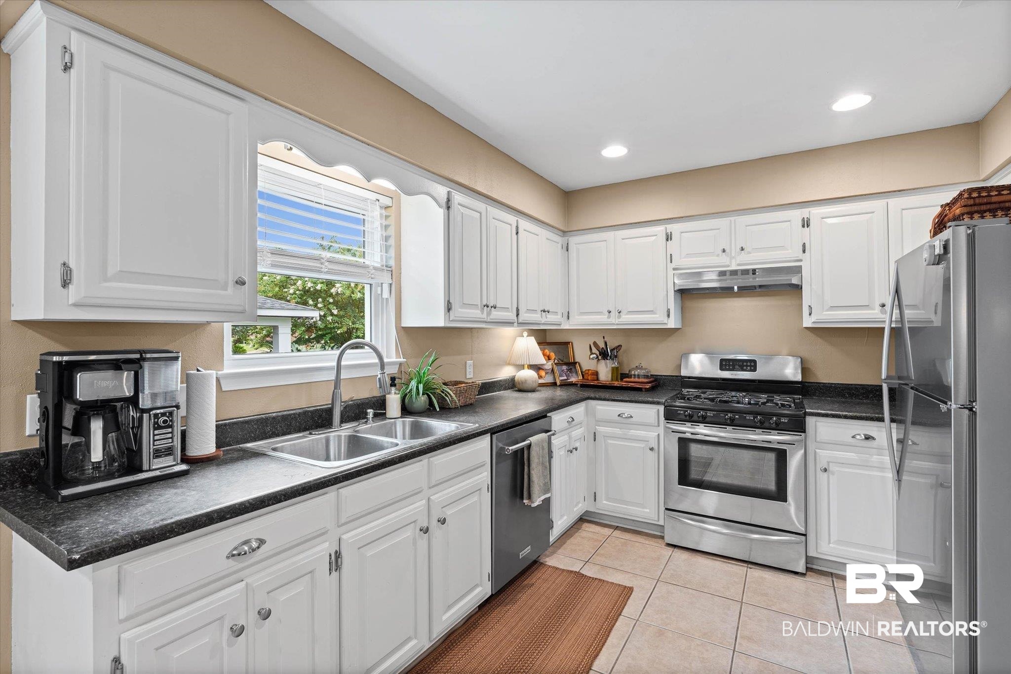 6501 Gas Light Lane South Mobile, AL 36695 - Photo 6 of 23 Kitchen featuring white cabinetry, dark countertops, stainless steel appliances, a double basin sink, and tile flooring