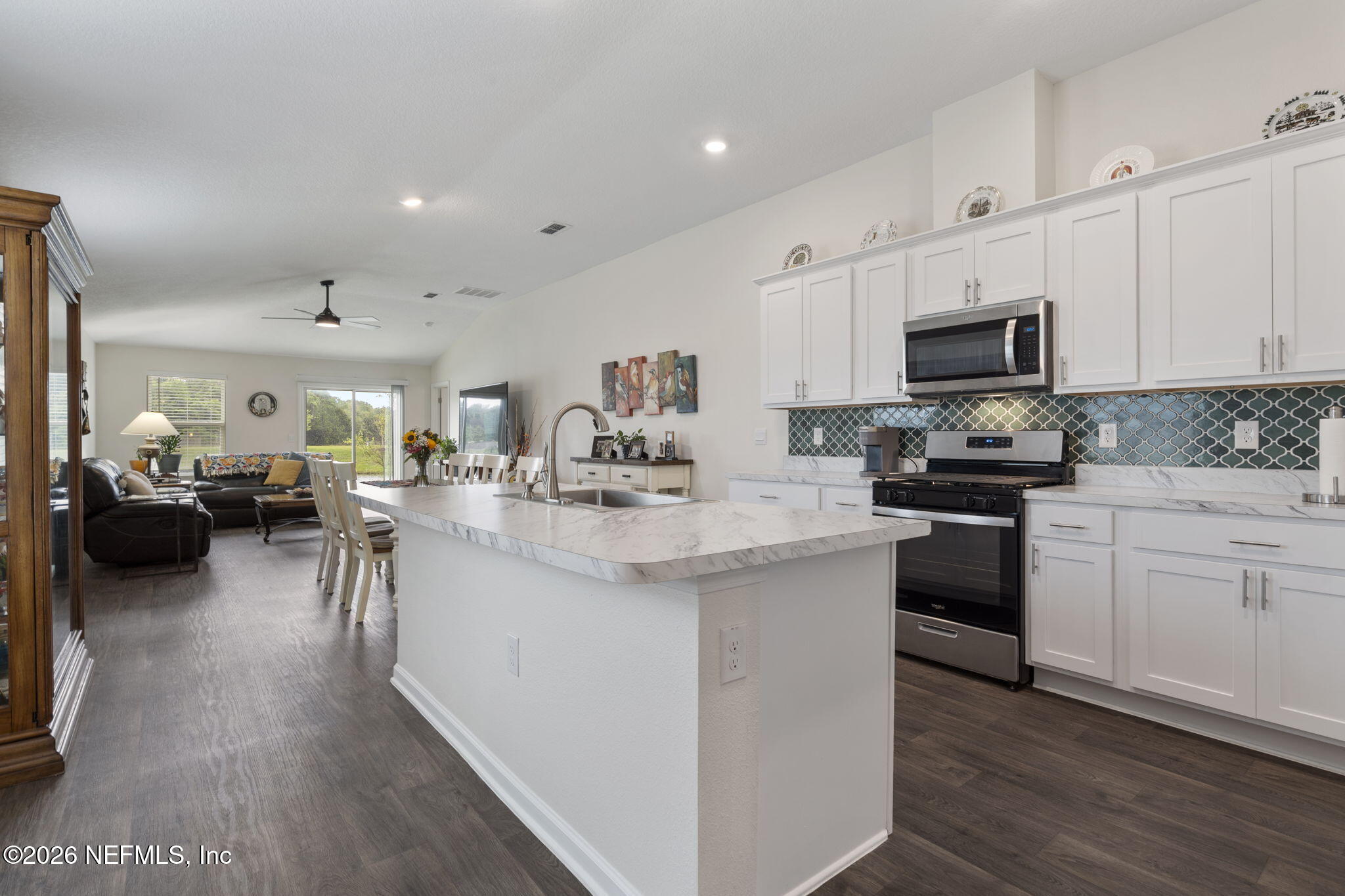 65 Mula Ct Street St. Augustine, FL 32084 - Photo 10 of 38 a kitchen with stainless steel appliances kitchen island granite countertop a stove top oven a sink a dining table and chairs with wooden floor