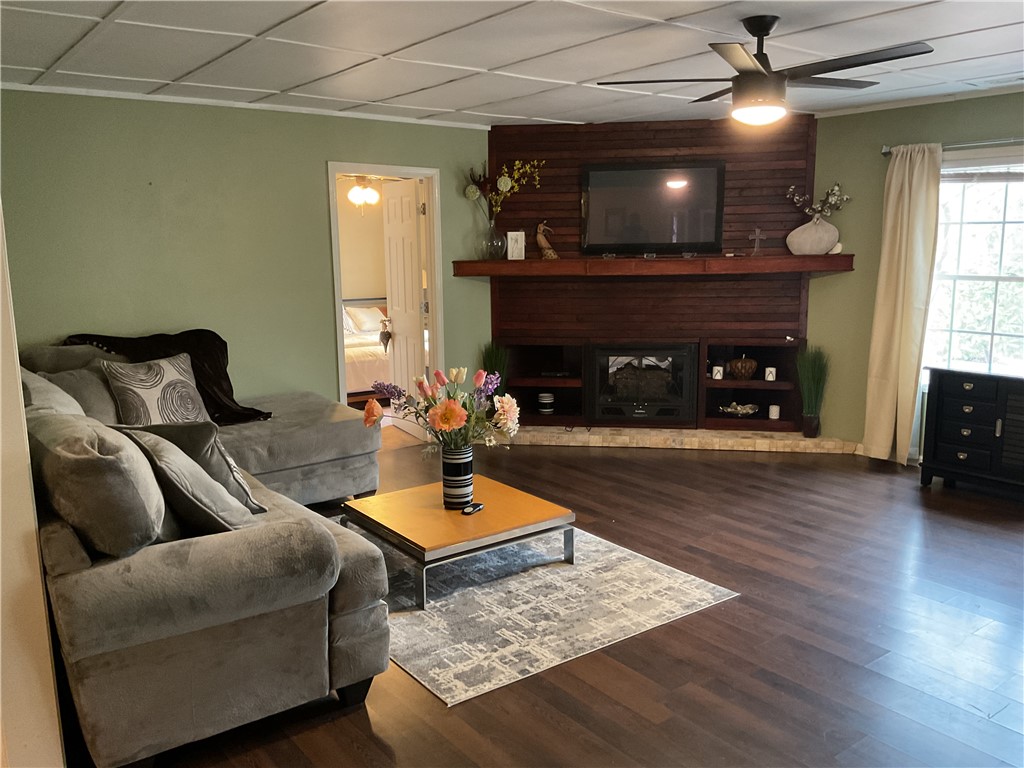 229 Cub Cove Drive Walhalla, SC 29691 - Photo 2 of 50 This living room features a captivating fireplace, dark wood flooring, and a ceiling fan.