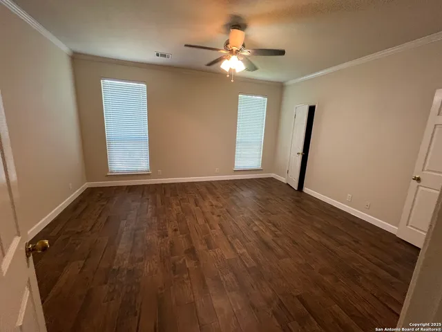 a view of an empty room with a window and wooden floor