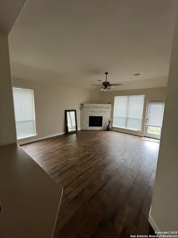 an empty room with wooden floor cabinet and windows