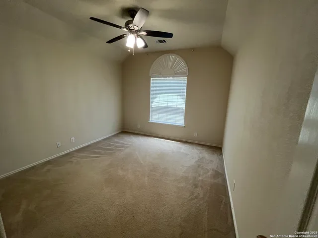 an empty room with a chandelier fan and windows
