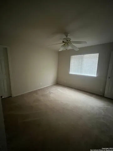 an empty room with a window and a ceiling fan