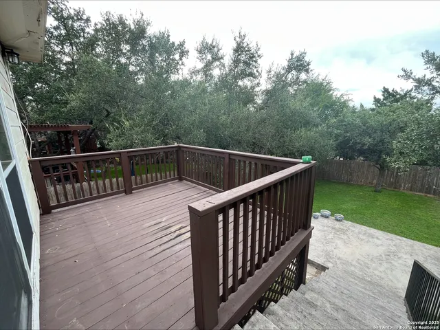 a balcony with wooden floor and trees in the background