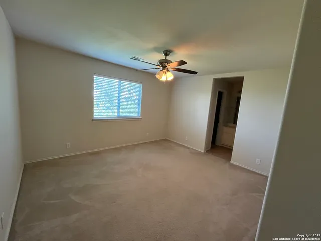 an empty room with a window and a fan