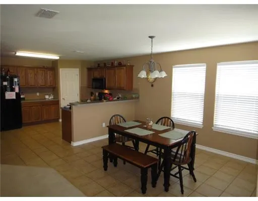 a kitchen with a dining table chairs and a refrigerator