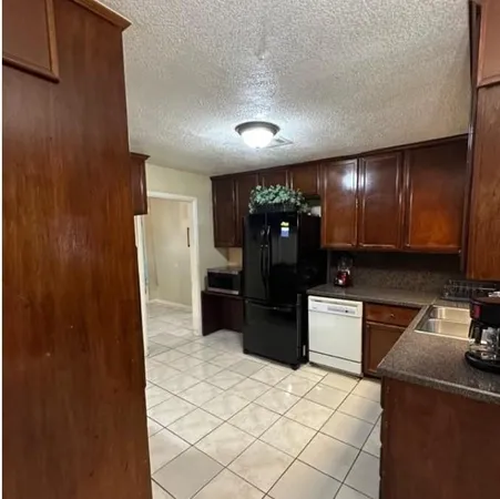 a kitchen with granite countertop a refrigerator and a stove top oven