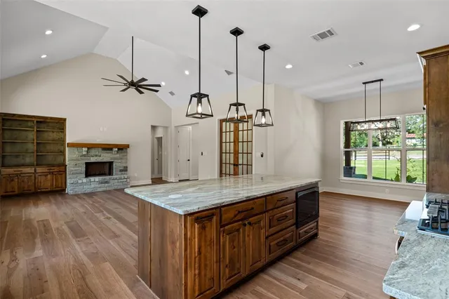 a kitchen with kitchen island a wooden floor stainless steel appliances and living room view