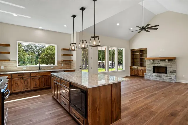 a kitchen with kitchen island granite countertop a stove a sink and wooden floors