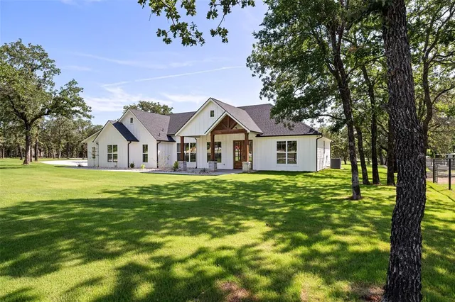 a view of a house with a big yard and large trees