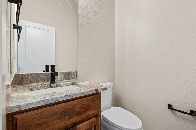 a bathroom with a granite countertop toilet sink and mirror
