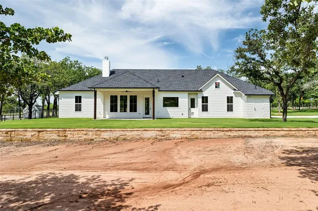 a view of a house with a big yard and large trees