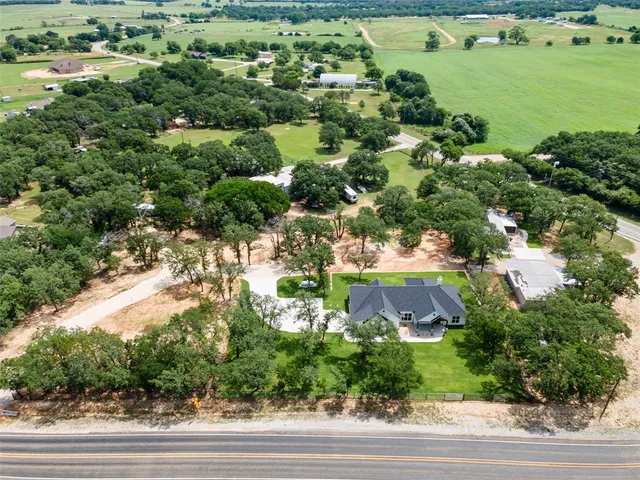 an aerial view of residential houses with outdoor space and trees