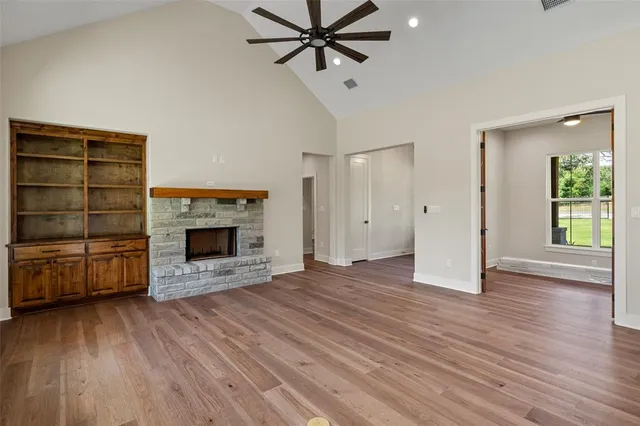 a view of a livingroom with a fireplace a ceiling fan and a kitchen counter top space