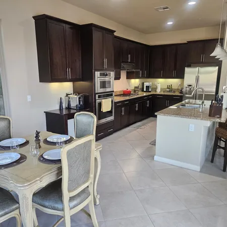 a kitchen with a sink a stove a refrigerator cabinets and chairs
