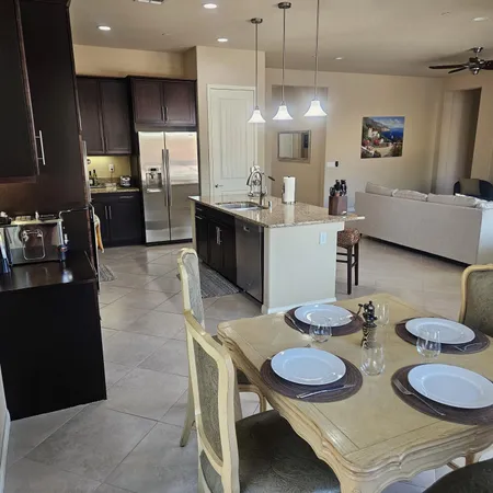 a kitchen with stainless steel appliances granite countertop a sink a stove a dining table and chairs