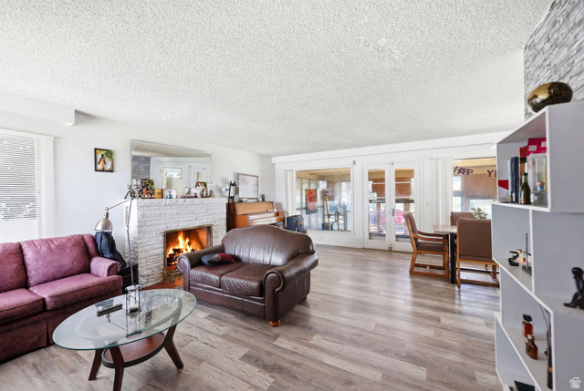 5480 South 2000th Street West Roy, UT 84067 - Photo 11 of 36 Spacious living area featuring wood-finish flooring, a white brick-clad fireplace, and multiple windows