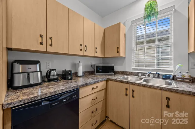 a kitchen with granite countertop stainless steel appliances a sink window and cabinets