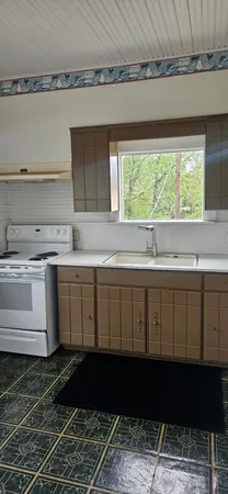 a kitchen with a sink a stove cabinets and a window