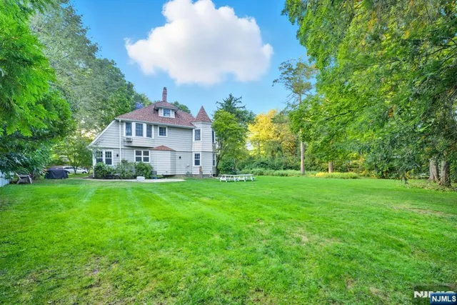 a view of a house with a big yard and large trees