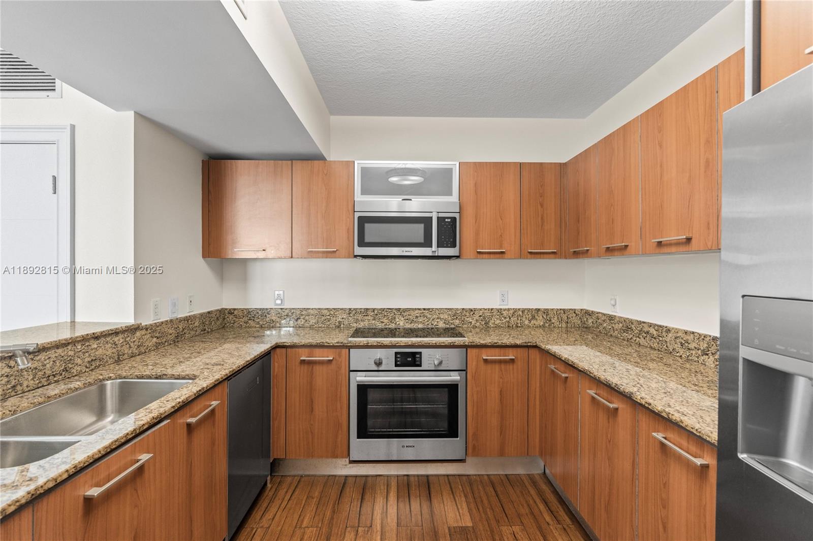 9055 Southwest 73rd Court, Unit 1502 Miami, FL 33156 - Photo 12 of 41 a kitchen with granite countertop wooden cabinets and white appliances