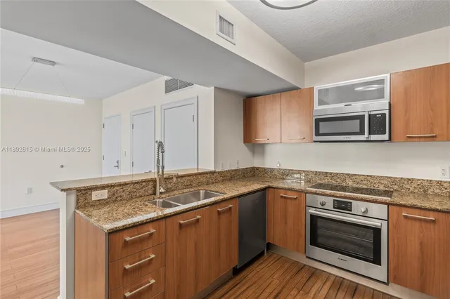 a kitchen with granite countertop a sink and steel appliances