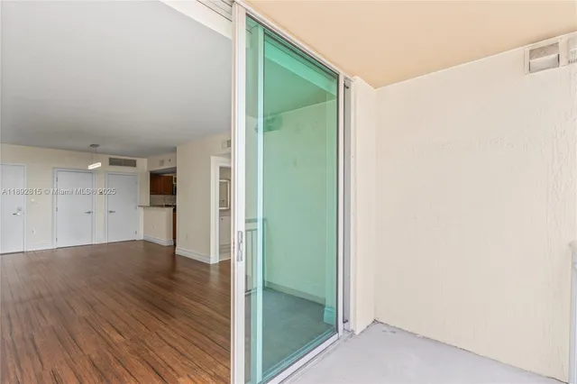 an empty room with wooden floor and a bathroom