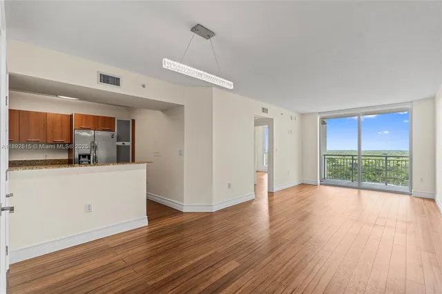a view of a big room with wooden floor and windows