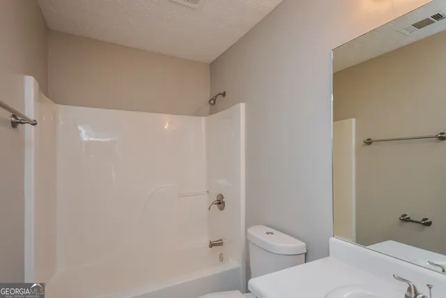 a bathroom with a granite countertop toilet a sink and shower