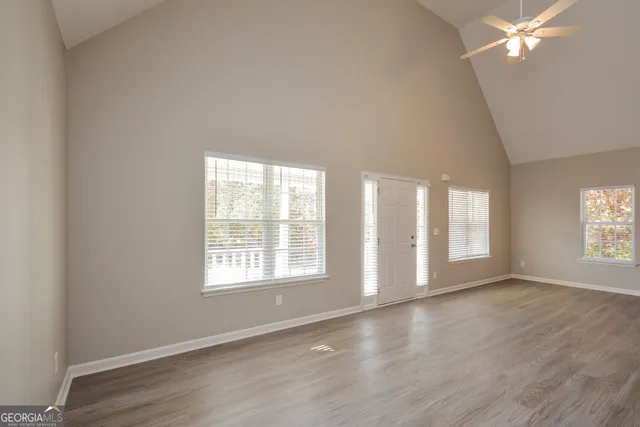 an empty room with wooden floor and windows