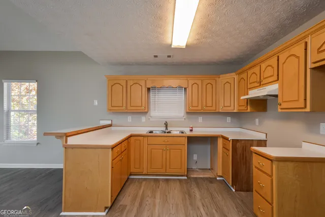 a kitchen with stainless steel appliances granite countertop wooden cabinets a sink a stove a refrigerator and dishwasher with wooden floor